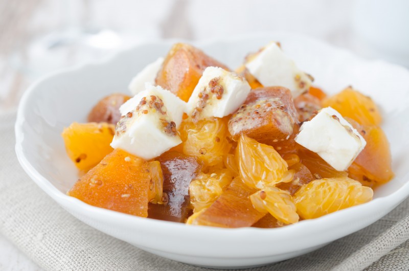salad with persimmon, mandarin oranges and goat cheese with mustard dressing closeup